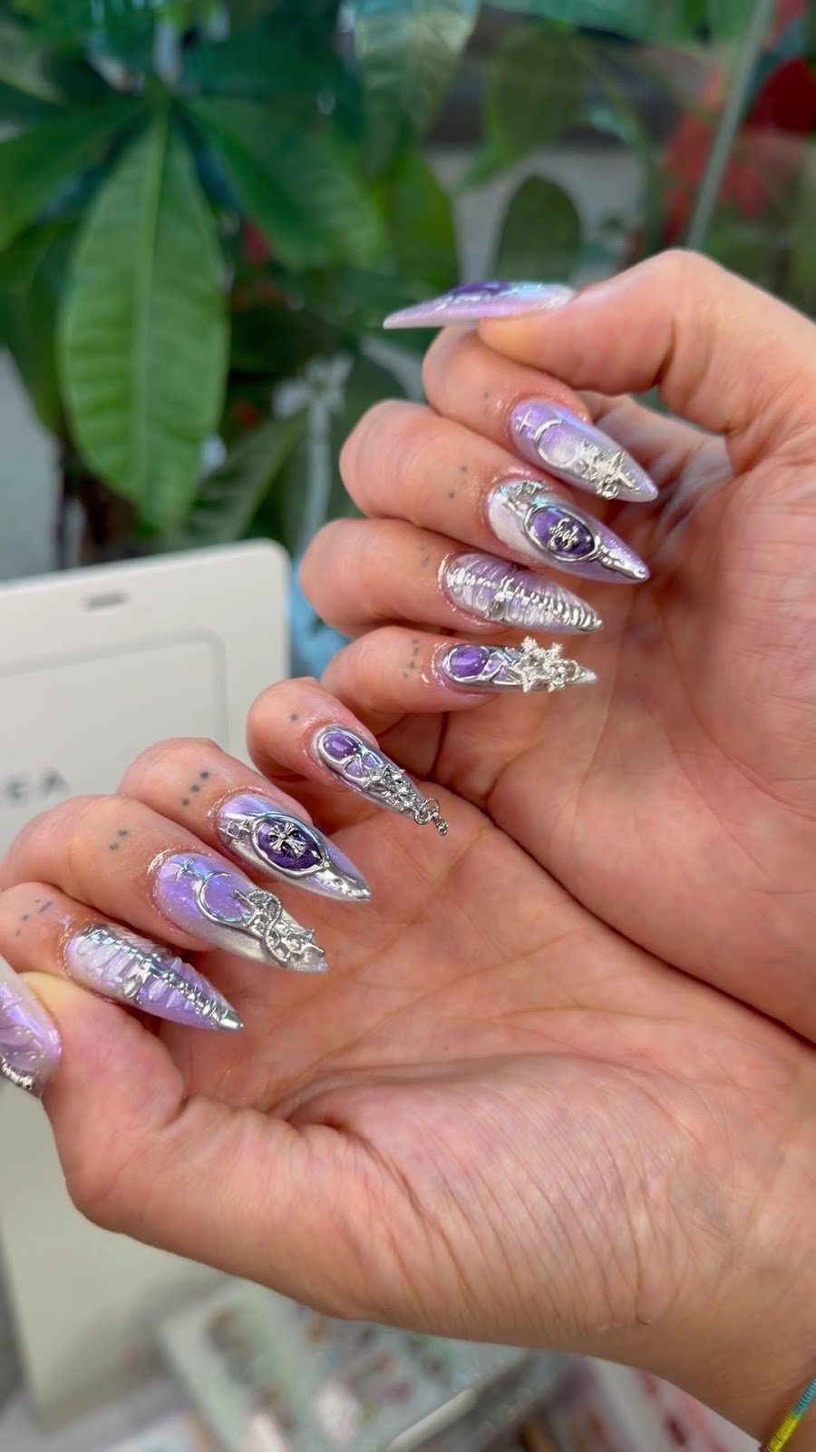 Purple chrome gel nail art with silver charms at Swizzy Beauty Bar Flushing